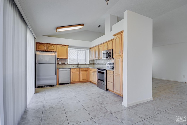 kitchen with lofted ceiling, stainless steel appliances, a sink, light countertops, and backsplash