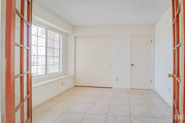 unfurnished room with a textured ceiling and light tile patterned flooring