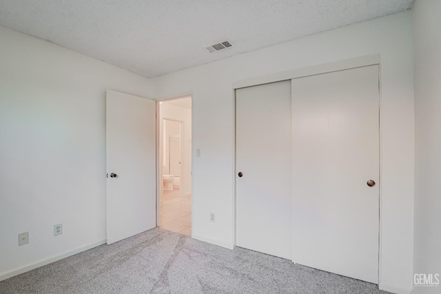 unfurnished bedroom with visible vents, a closet, carpet flooring, and a textured ceiling