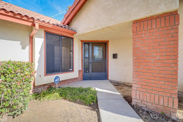 entrance to property featuring stucco siding and a tiled roof