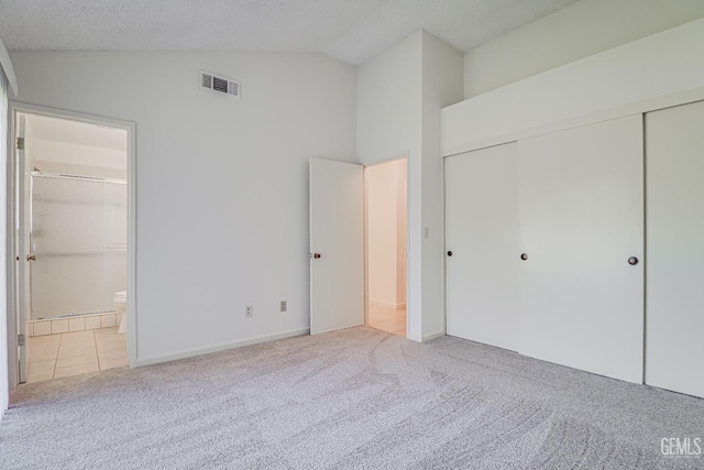 unfurnished bedroom with carpet floors, a closet, visible vents, connected bathroom, and vaulted ceiling