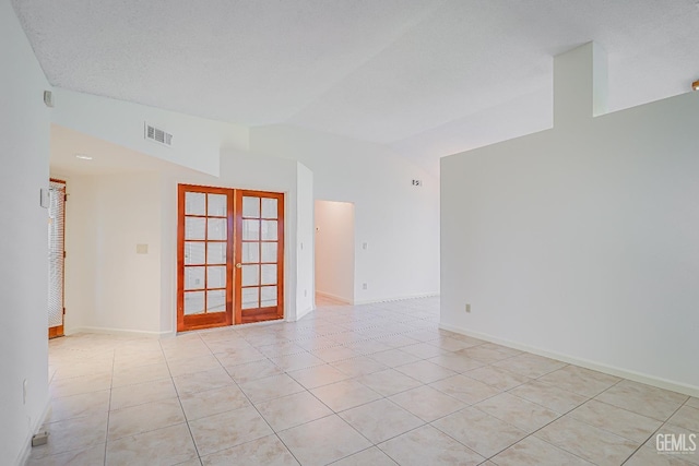 empty room with lofted ceiling, light tile patterned floors, visible vents, and french doors