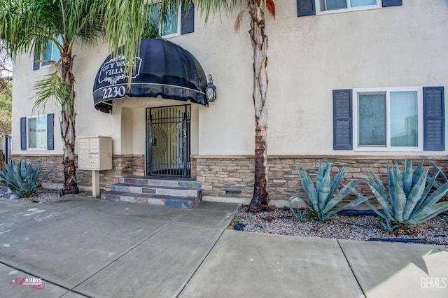 doorway to property featuring stone siding and stucco siding