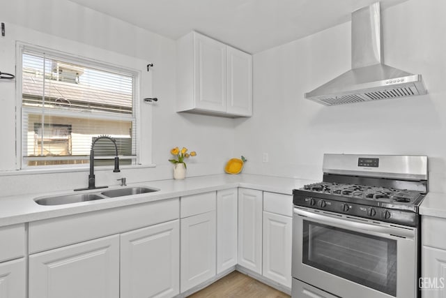304 Wilson Ave, Bakersfield, CA 93308 - kitchen with stainless steel gas stove, wall chimney exhaust hood, a sink, white cabinets, and light countertops