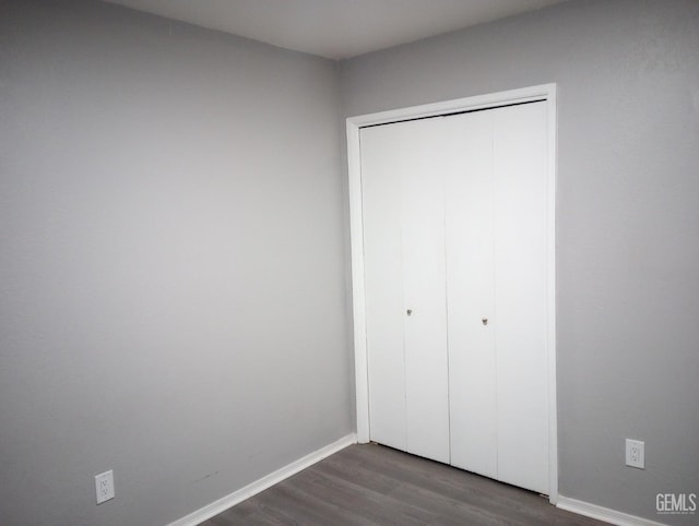 unfurnished bedroom with dark hardwood / wood-style floors and a closet