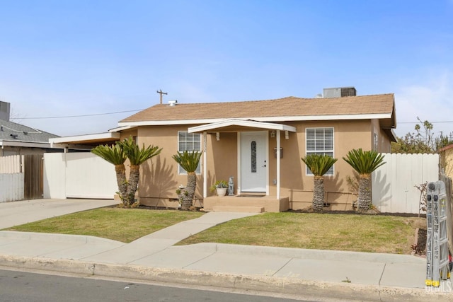 view of front of home featuring stucco siding, concrete driveway, central AC unit, fence, and a front lawn