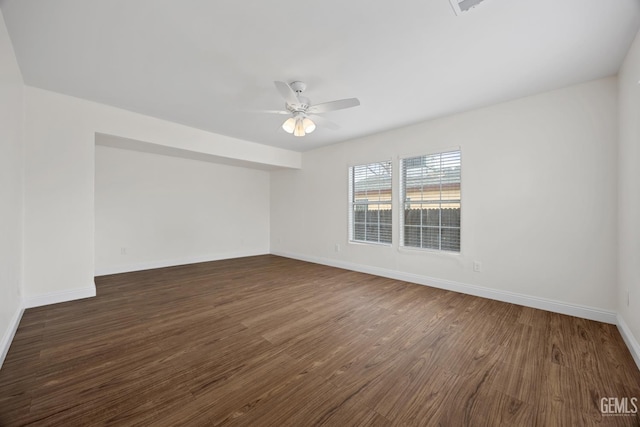 empty room with ceiling fan, dark wood-type flooring, and baseboards