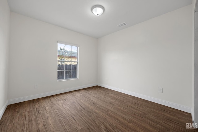 spare room with baseboards, visible vents, and dark wood finished floors