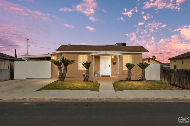 view of front of property with a yard, fence, and stucco siding