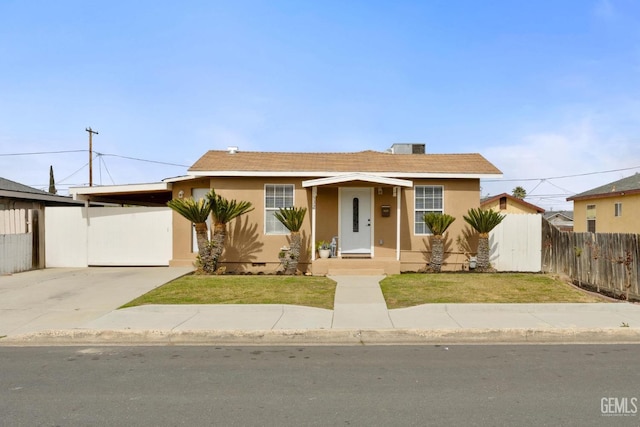 bungalow featuring an attached carport, a front yard, fence, and stucco siding