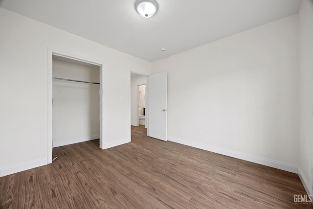 unfurnished bedroom with a closet, wood finished floors, and baseboards