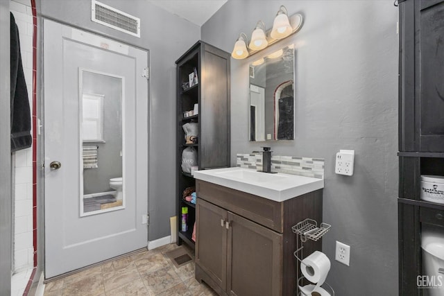 bathroom with vanity, backsplash, and toilet