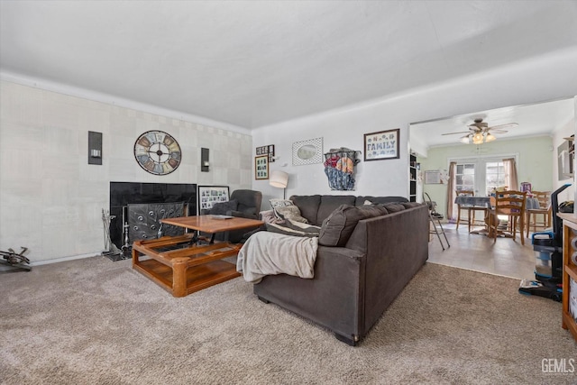 living room featuring a tile fireplace, ceiling fan, and carpet