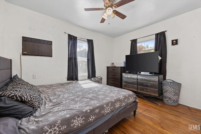 bedroom featuring hardwood / wood-style flooring, ceiling fan, and multiple windows