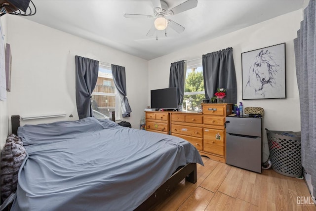 bedroom featuring stainless steel refrigerator, ceiling fan, and light hardwood / wood-style flooring