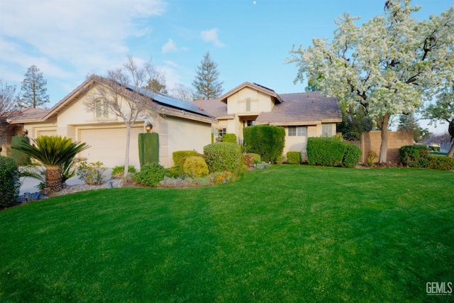 view of front of property featuring a garage, solar panels, and a front lawn