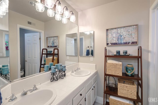 bathroom with an inviting chandelier, vanity, and toilet