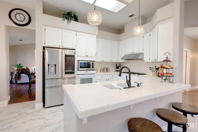 kitchen with sink, backsplash, hanging light fixtures, kitchen peninsula, and stainless steel appliances