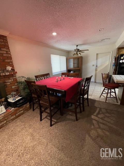 dining area with light carpet, a textured ceiling, and ornamental molding