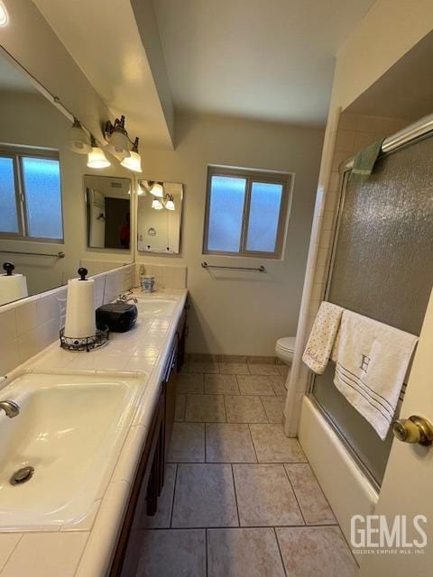 full bathroom featuring shower / bath combination with glass door, tile patterned floors, vanity, and toilet