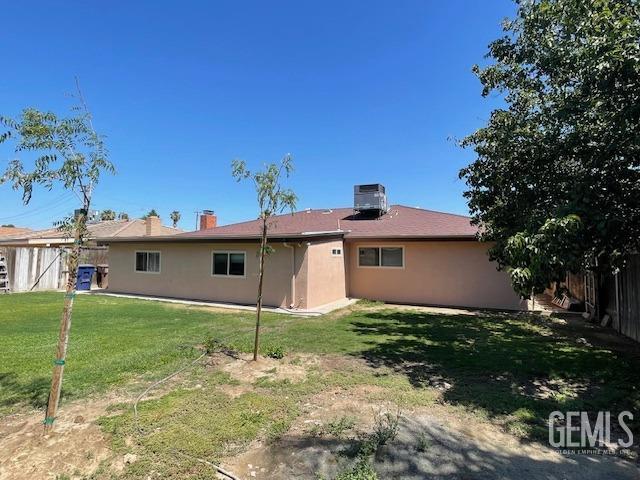 back of property with cooling unit and a lawn