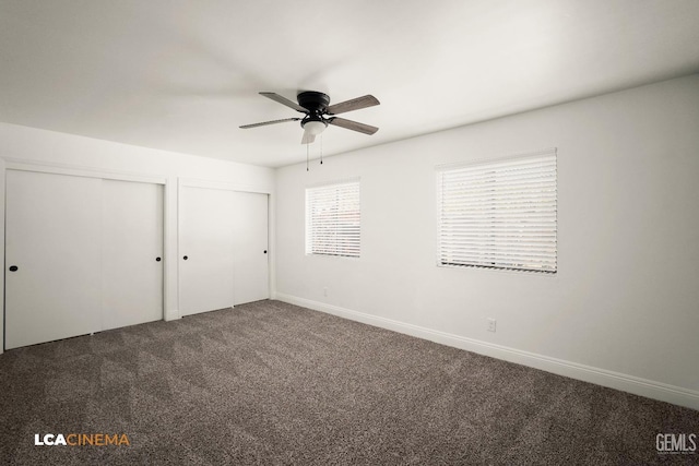 unfurnished bedroom featuring baseboards, carpet floors, ceiling fan, and multiple closets