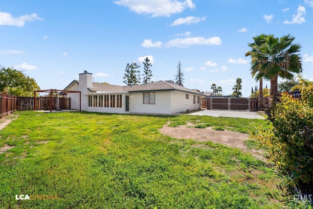 back of property with a fenced backyard, a yard, and a gate