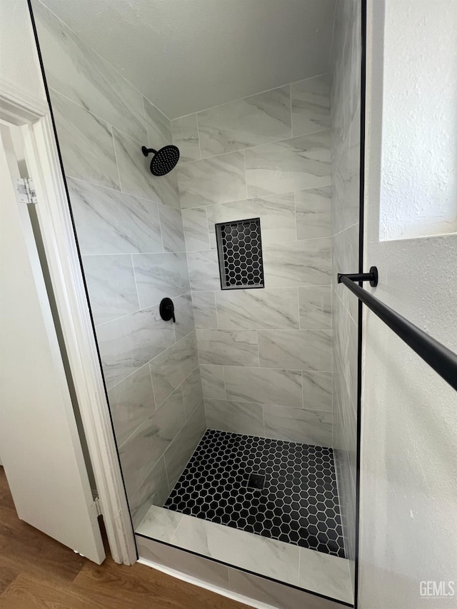 full bath with a shower stall and wood finished floors