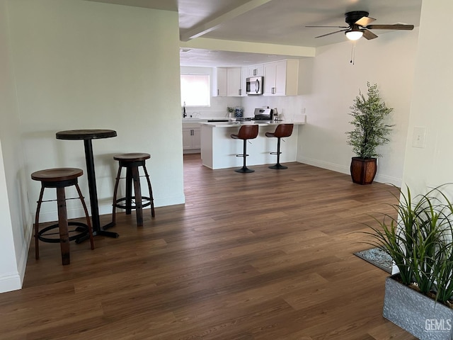 kitchen with white cabinetry, dark wood-type flooring, a kitchen breakfast bar, and appliances with stainless steel finishes