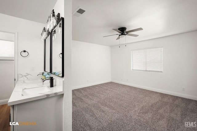 unfurnished living room with visible vents, baseboards, carpet floors, a ceiling fan, and a sink