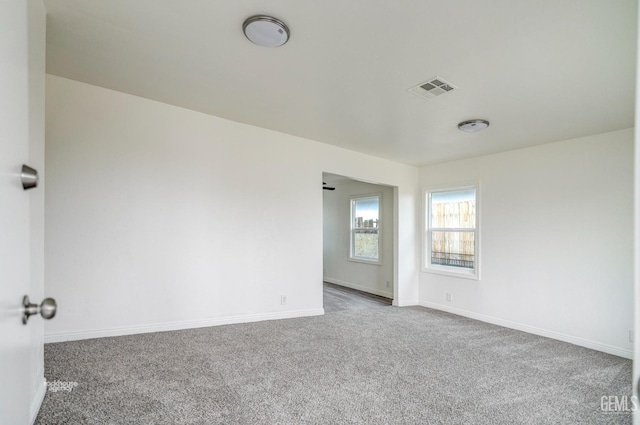 carpeted empty room featuring baseboards and visible vents