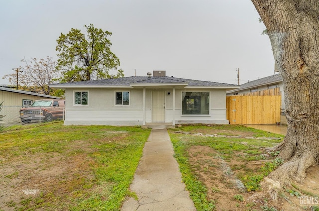 view of front facade featuring a front yard, roof with shingles, and fence