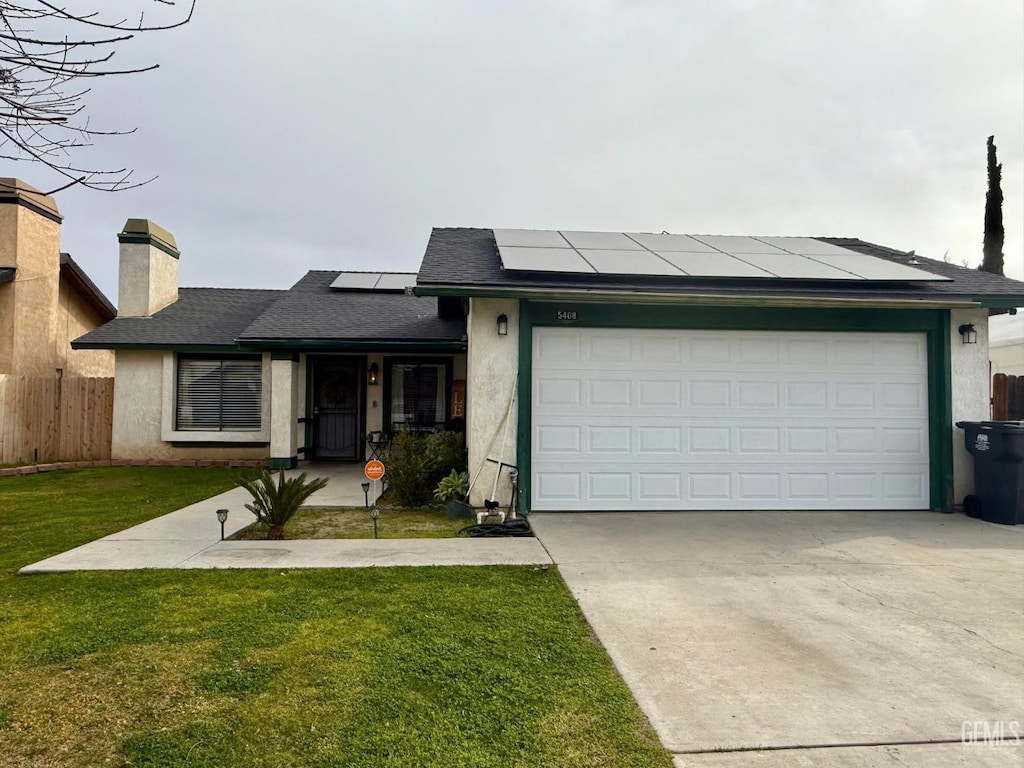 view of front of property with a garage, a front lawn, and solar panels