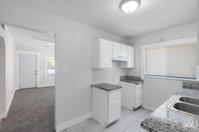 714 R St, Bakersfield, CA 93304 - kitchen with white cabinetry, under cabinet range hood, and a textured ceiling