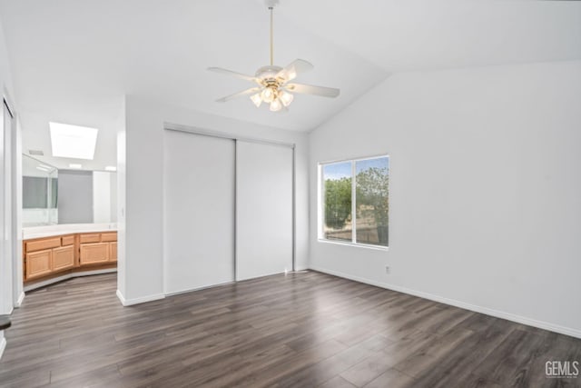 unfurnished bedroom featuring connected bathroom, dark wood-style flooring, a skylight, and a closet