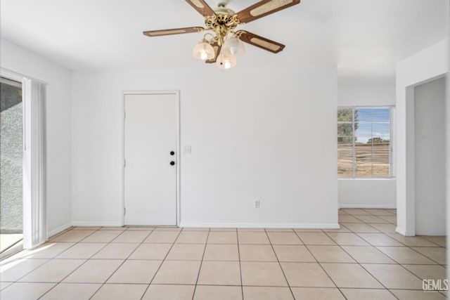 spare room featuring light tile patterned floors, baseboards, and a ceiling fan