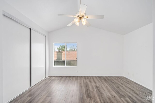 spare room with baseboards, lofted ceiling, wood finished floors, and ceiling fan