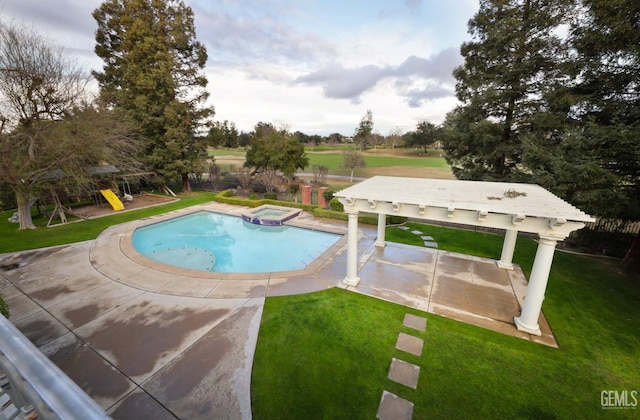 view of swimming pool with a playground, fence, a pool with connected hot tub, a lawn, and a patio area