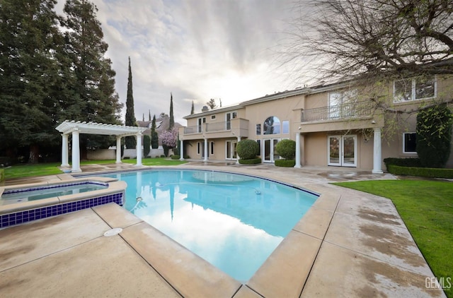 view of swimming pool featuring a patio, a pool with connected hot tub, a yard, french doors, and a pergola