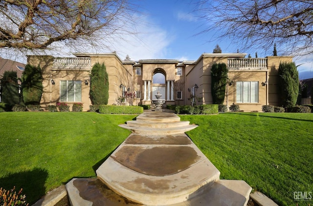 mediterranean / spanish-style home with a front lawn, a balcony, and stucco siding