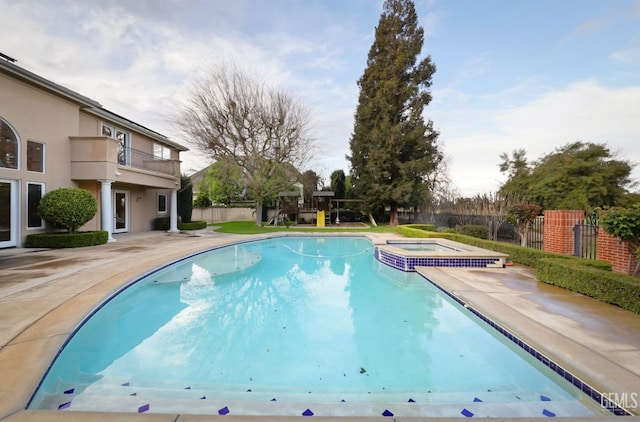 view of pool featuring a patio, fence, and a pool with connected hot tub