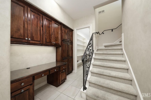 interior space featuring tile patterned floors, visible vents, baseboards, and built in study area