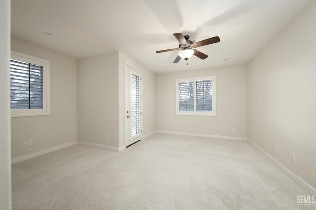 empty room with light colored carpet, ceiling fan, and baseboards