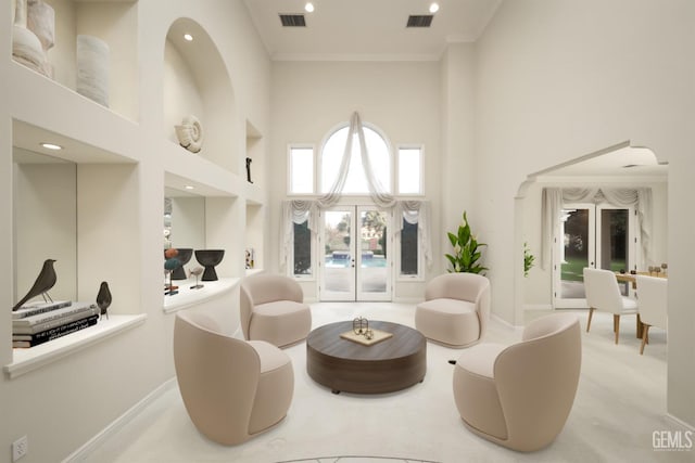 living area featuring ornamental molding, visible vents, and a high ceiling