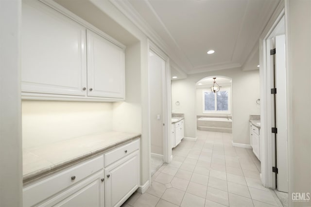 interior space featuring light tile patterned floors, arched walkways, baseboards, ornamental molding, and recessed lighting