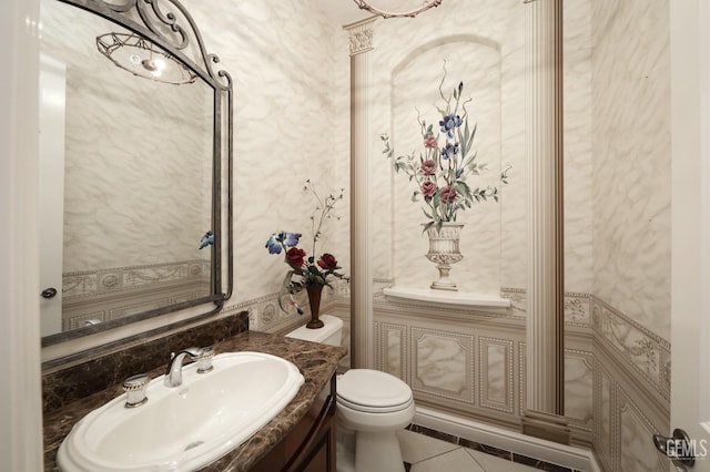 half bathroom featuring tile patterned flooring, vanity, and toilet