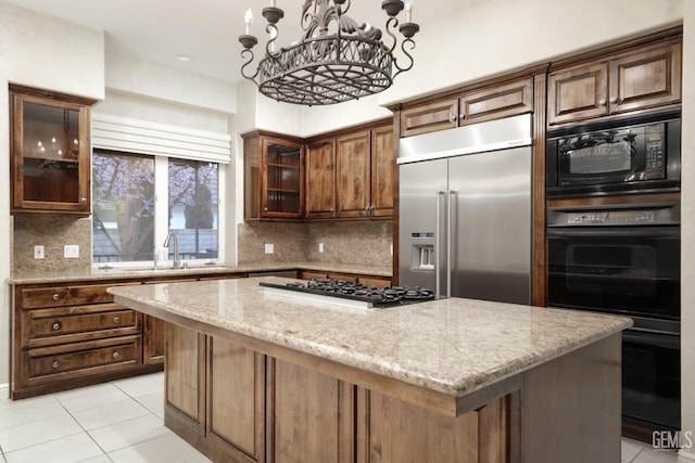 kitchen featuring light stone counters, light tile patterned flooring, a kitchen island, a sink, and black appliances