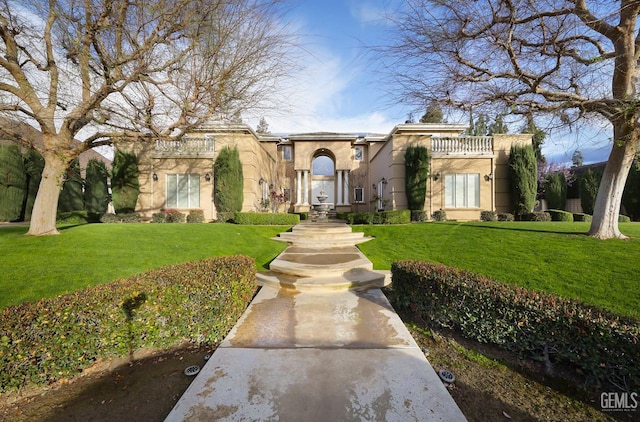 mediterranean / spanish-style home featuring a balcony, a front lawn, and stucco siding