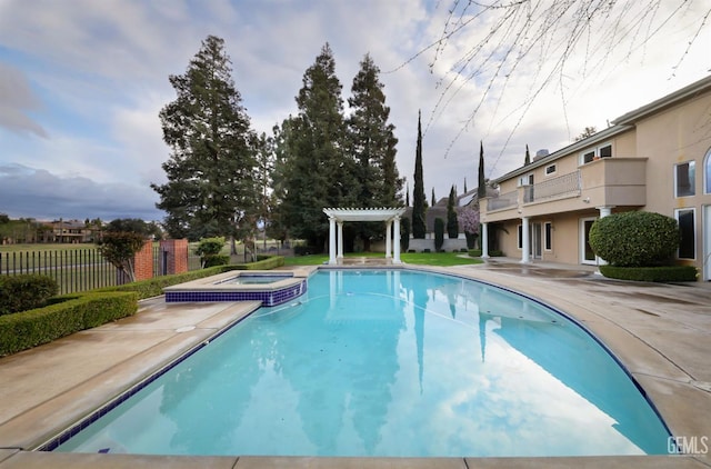 view of swimming pool featuring a pool with connected hot tub, fence, a pergola, and a patio