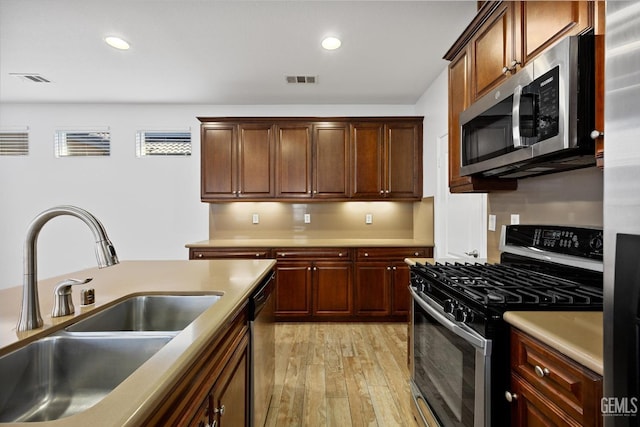 kitchen with light wood-type flooring, sink, and appliances with stainless steel finishes